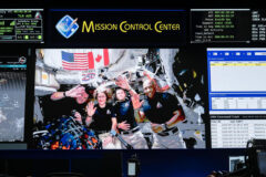 The Artemis II crew – CSA (Canadian Space Agency) Astronaut Jeremy Hansen (far left) and NASA astronauts Christina Koch (center left), Reid Wiseman (center right), and Victor Glover (right) – pauses to wave after a live conversation with President Donald J. Trump following their historic lunar flyby during Flight Day 6. They are pictured on the screens of the White Flight Control room at NASA’s Mission Control Center at the agency’s Johnson Space Center in Houston. (NASA/Robert Markowitz)